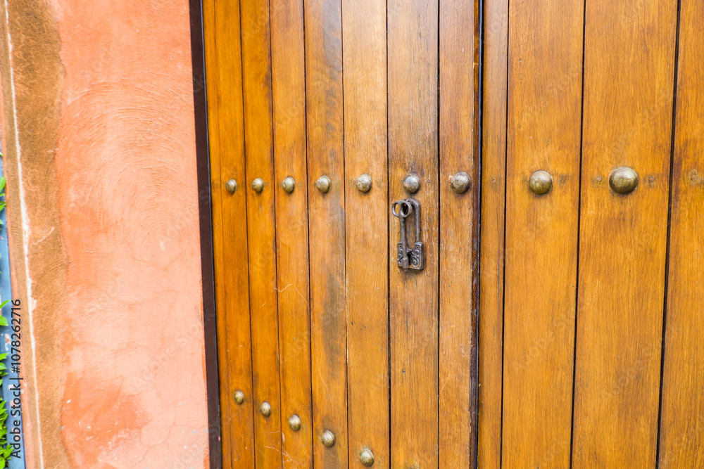 Fototapeta premium Close up of old Key in wooden door at home, Brown Wood Front Door with Ornate Brass Skeleton Key,copy space..