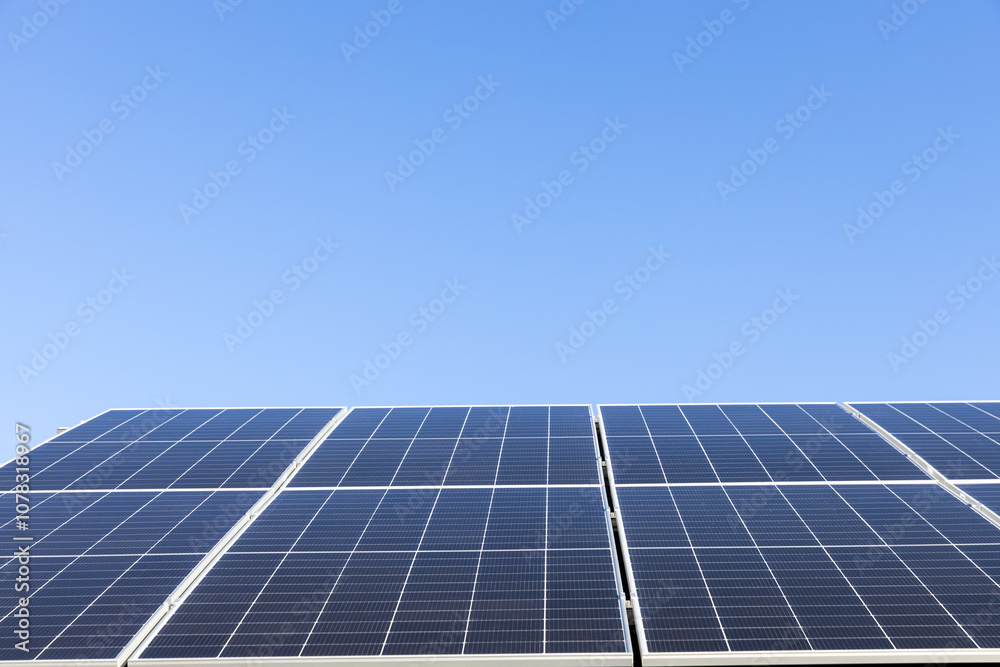 Aerial view of solar panel cells on clear blue sky background. Alternative energy concept. Modern house with solar panels stand-alone photovoltaic plant system on household metal sheet roof Aerial view of solar panel cells on clear blue sky background. Alternative energy concept. Modern house with solar panels stand-alone photovoltaic plant system on household metal sheet roof
