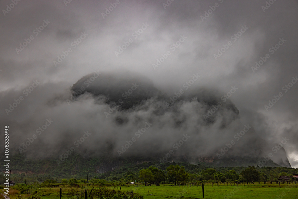Before the rain falls, the tall mountain is covered with dark clouds. A beautiful rice field is in front of the tall mountain, making the atmosphere mysterious and interesting. Before the rain falls, the tall mountain is covered with dark clouds. A beautiful rice field is in front of the tall mountain, making the atmosphere mysterious and interesting.