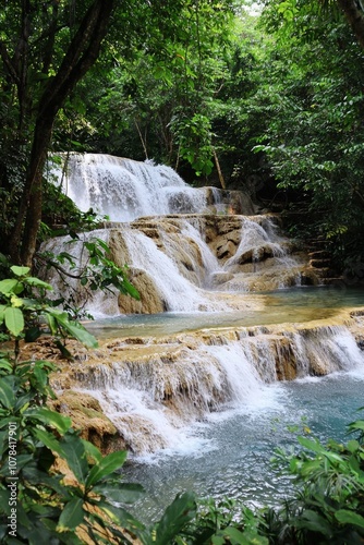 A beautiful waterfall in the jungle, with blue water and green trees, creating a fantasy landscape.