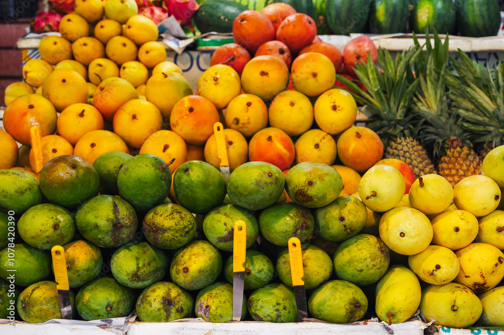 A colorful fruit display case made of mangoes and pineapples on display at the local market