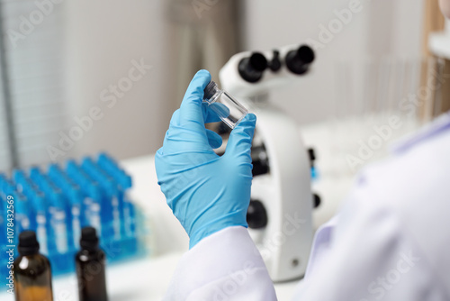 Scientist Holding Sample in Modern Laboratory with Microscope and Test Tubes for Scientific Research and Analysis