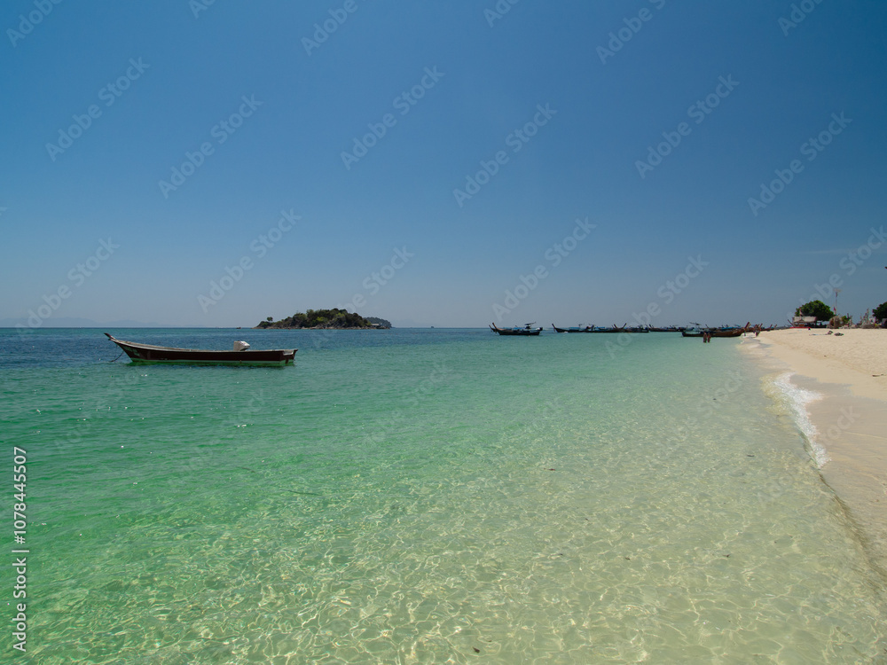 Fototapeta premium Serene Tropical Beach with Turquoise Waters and Longtail Boat in Thailand, Koh Lipe