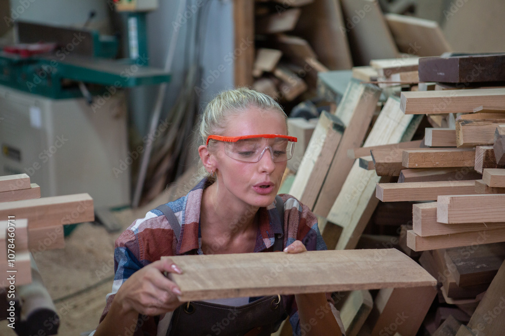 young carpenter woman wear uniform and goggles choose the size and quality wood used for work. craftsman professional concept. woodworking industry. young carpenter woman wear uniform and goggles choose the size and quality wood used for work. craftsman professional concept. woodworking industry.