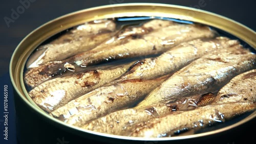 Fish in a can of oil rotates on a black background, close-up. Sprats. Seafood