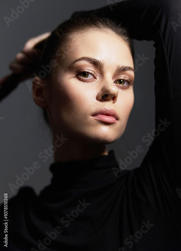 Confident woman with sleek hair, posing in a black turtleneck, exuding elegance and grace against a dark background. Studio portrait emphasizing beauty and sophistication. photo