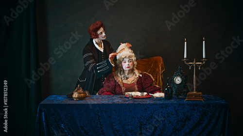 Loyal court favorite brushes wig of elegantly dressed empress, elderly woman in period attire, with serious face, sitting at table with serious face. Concept of history, comparison of eras photo