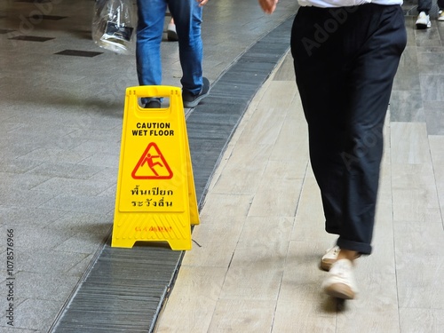 Obraz na plátně A caution wet floor sign in a busy walkway, reminding pedestrians to be careful and avoid slipping hazards