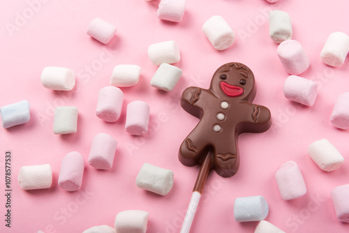 Chocolate man on pink background with marshmallows , sweet Christmas cookies, top view