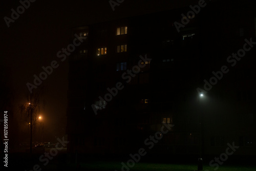 Wallpaper Mural The scene depicts a foggy night, showcasing an apartment building with its illuminated windows, which together create a captivating and mysterious atmosphere in the urban landscape of the city Torontodigital.ca