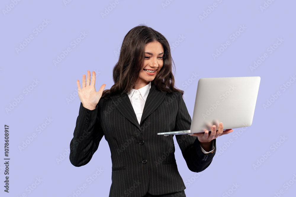 Businesswoman smiling and waving while video calling on a laptop in a professional setting Businesswoman smiling and waving while video calling on a laptop in a professional setting