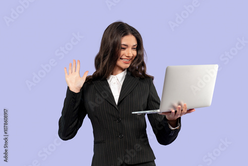 Businesswoman smiling and waving while video calling on a laptop in a professional setting