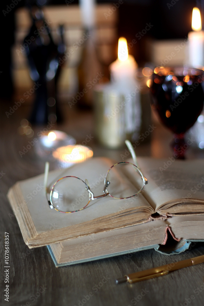 Books, lit candles, red wine, snacks and various deocration on the table. Dark academia or Halloween concept. Selective focus.