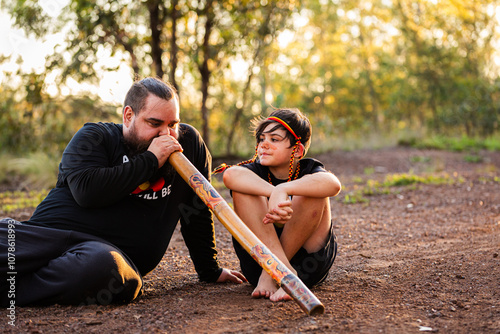 First Nations Australian father teaching Aboriginal son to play didgeridoo in rural Australia