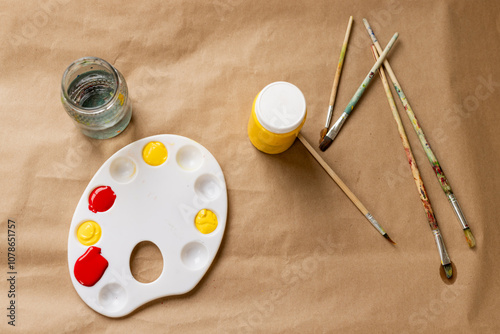 Art supplies arranged on table with paint palette, brushes, and water jar, at home photo