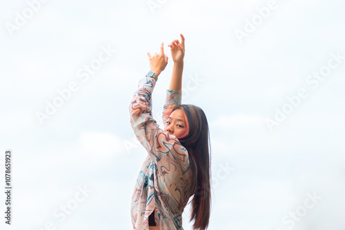 Asian woman with raised arms in serene outdoor setting photo