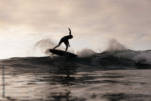 Surfer silhouette riding a wave in dramatic lighting photo