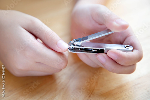 Girl cutting finger nail; Kid hand with nail clipper