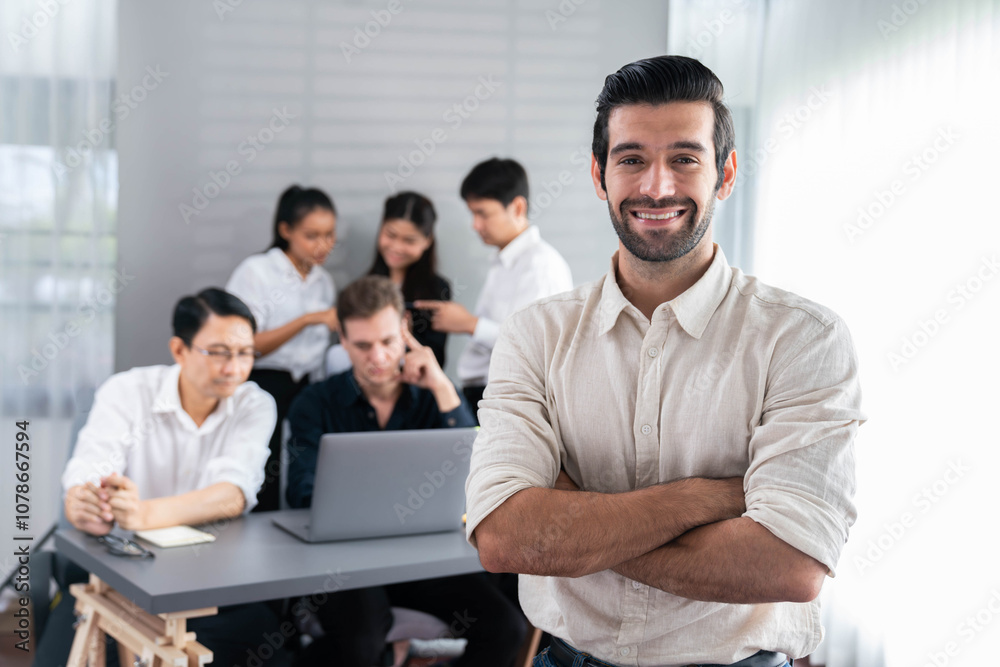 Confidence and happy smiling businessman portrait with background of his colleague and business team working in office. Office worker teamwork and positive workplace concept. Prudent Confidence and happy smiling businessman portrait with background of his colleague and business team working in office. Office worker teamwork and positive workplace concept. Prudent