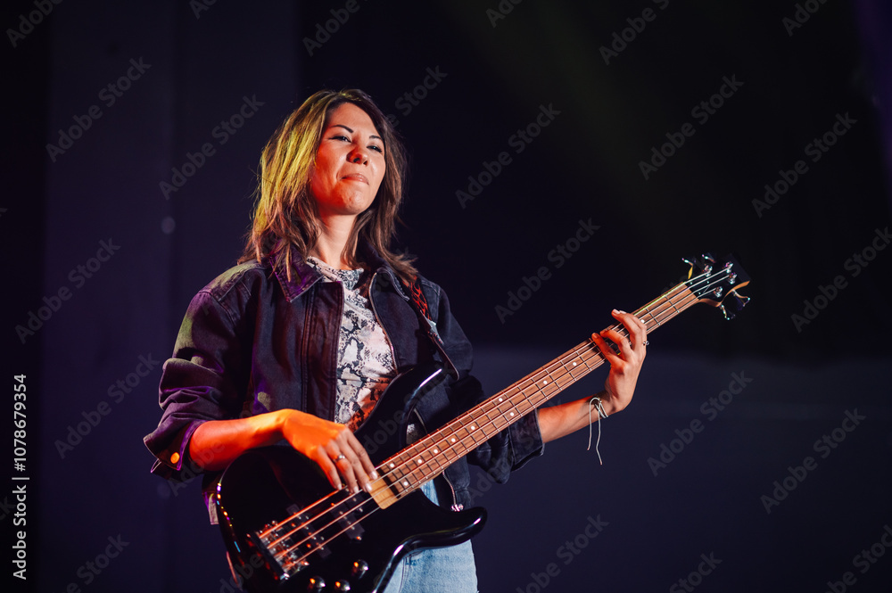 Obraz premium Female musician performing on stage with bass guitar