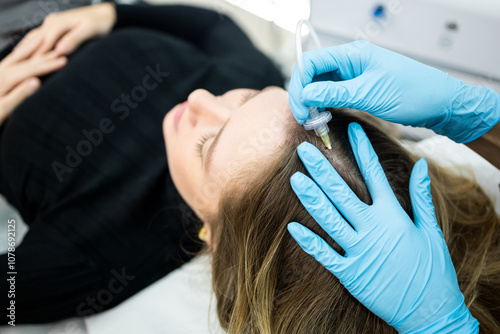 A young blonde woman undergoing carboxytherapy to stimulate circulation in the scalp, improving the supply of nutrients and oxygen to increase hair growth.Concept of carboxytherapy. photo