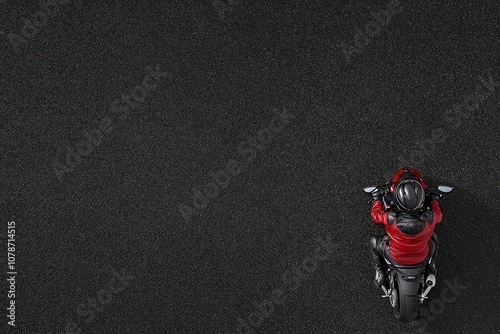 A lone motorcyclist rides on a black asphalt road, seen from above.