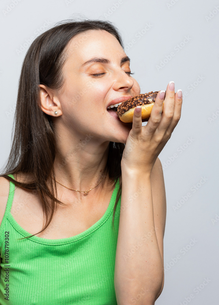 Happy woman biting into a delicious donut and enjoying it so much. On white background.