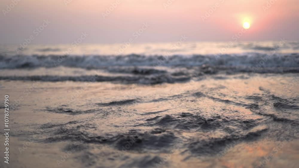 Sunset with ocean waves crashing on a beach in summer Sunset with ocean waves crashing on a beach in summer
