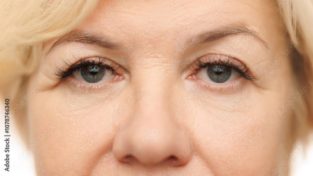 Close-up view of woman's eye, emphasizing wrinkles and calm, serene gaze against white studio background. Lashes and brows. Concept of natural beauty, spa treatment, cosmetology. Close-up view of woman's eye, emphasizing wrinkles and calm, serene gaze against white studio background. Lashes and brows. Concept of natural beauty, spa treatment, cosmetology.