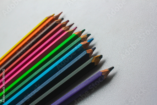 A collection of sharpened colored pencils arranged on a white surface, showcasing a vibrant array of colors. Perfect for themes related to art, education, and creativity.