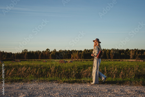 Fashionable woman walks along a gravel road in a rural setting