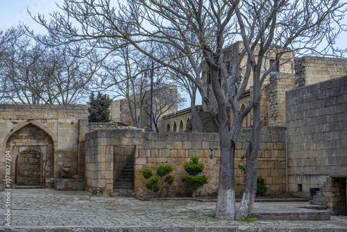 A courtyard with buildings made of stone blocks in the ancient city. Stone block walls and trees in a Persian fortress. Streets in an ancient fortress in the city of Derbent.