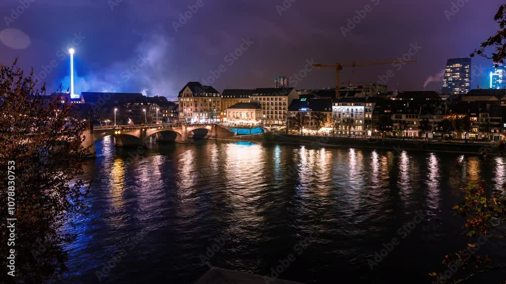 Timelapse of Basel at night with city lights reflecting on the Rhine River and a boat passing under the bridge. Captures the vibrant urban ambiance, ideal for cityscape and travel projects Timelapse of Basel at night with city lights reflecting on the Rhine River and a boat passing under the bridge. Captures the vibrant urban ambiance, ideal for cityscape and travel projects