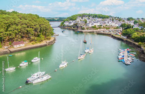 Photography Under blue skies, sailboats and fishing boats are moored in the calm waters of Le Bono Harbor near the Le Bono Suspension Bridge on a summer day
