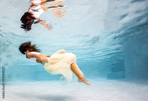 Young ballerina swimming in a pool underwater 