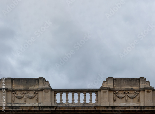 Old ornate stone balustrade balcony against a cloudy sky for use as a background