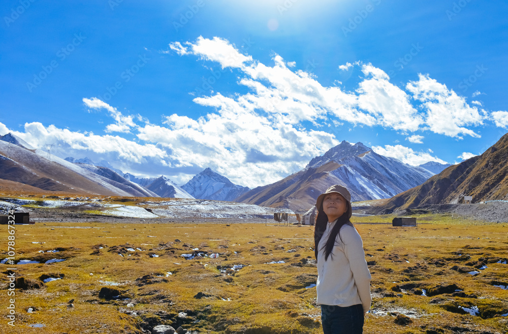Naklejka premium Asian woman enjoying beautiful autumn landscape of Bayanbulak Grassland along Duku Highway(Rd. G217), Korla, Xinjiang, China