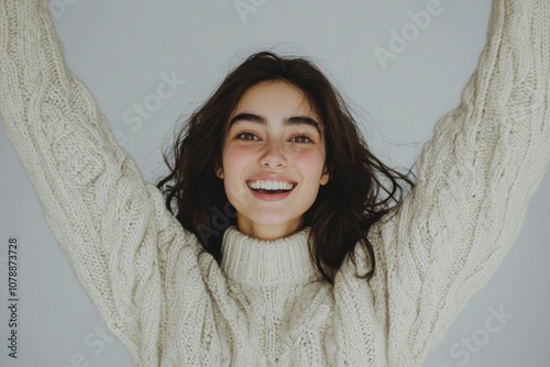 Excited Young Woman Celebrating Success in Sweater, Isolated on Grey Studio Background photo