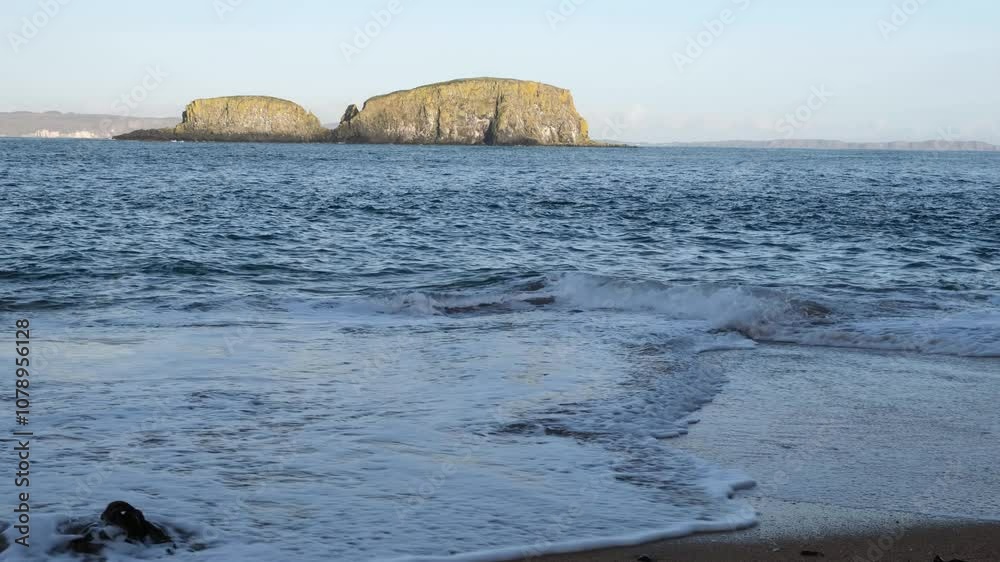 Waves breaking and sand churning in the shallow waters of the hidden beach at Ballintoy, no people. Beautiful rugged seascape, solitude, tranquillity, unspoiled.