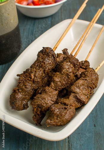 Maranggi satay on white plate over dark background with Indonesia sweet soy dipping sauce (sambal kecap) photo