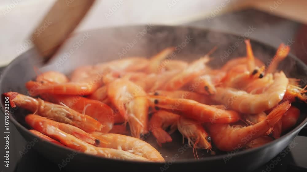 Chef frying shrimps in pan uses a wooden spatula. shrimps turn pink while releasing steam, creating an appetizing aroma in kitchen Chef frying shrimps in pan uses a wooden spatula. shrimps turn pink while releasing steam, creating an appetizing aroma in kitchen