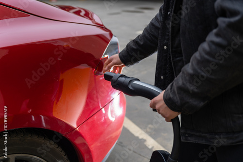 Hand Plugging Electric Car at Charging Station