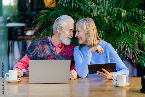 Elderly couple enjoying technology with laptops and tablets photo