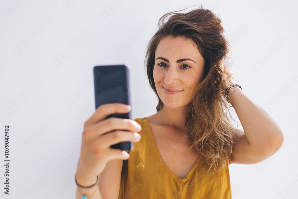 Smiling gorgeous lady in modern outfit capturing selfie photo by mobile on gray blank background Smiling gorgeous lady in modern outfit capturing selfie photo by mobile on gray blank background