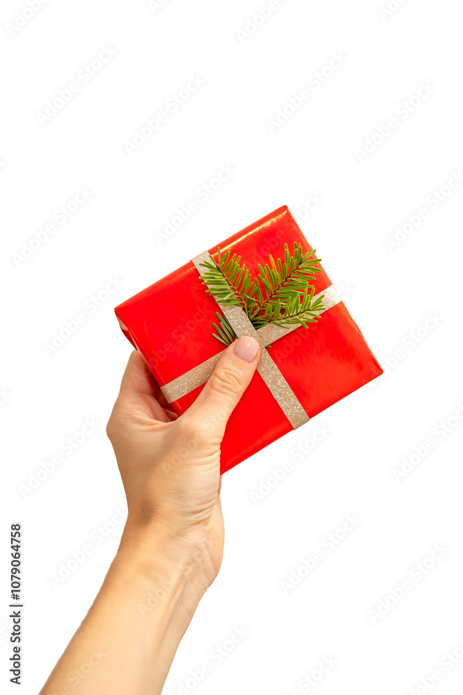 Female hand holding a small gift in a festive Christmas red package on a white background Female hand holding a small gift in a festive Christmas red package on a white background