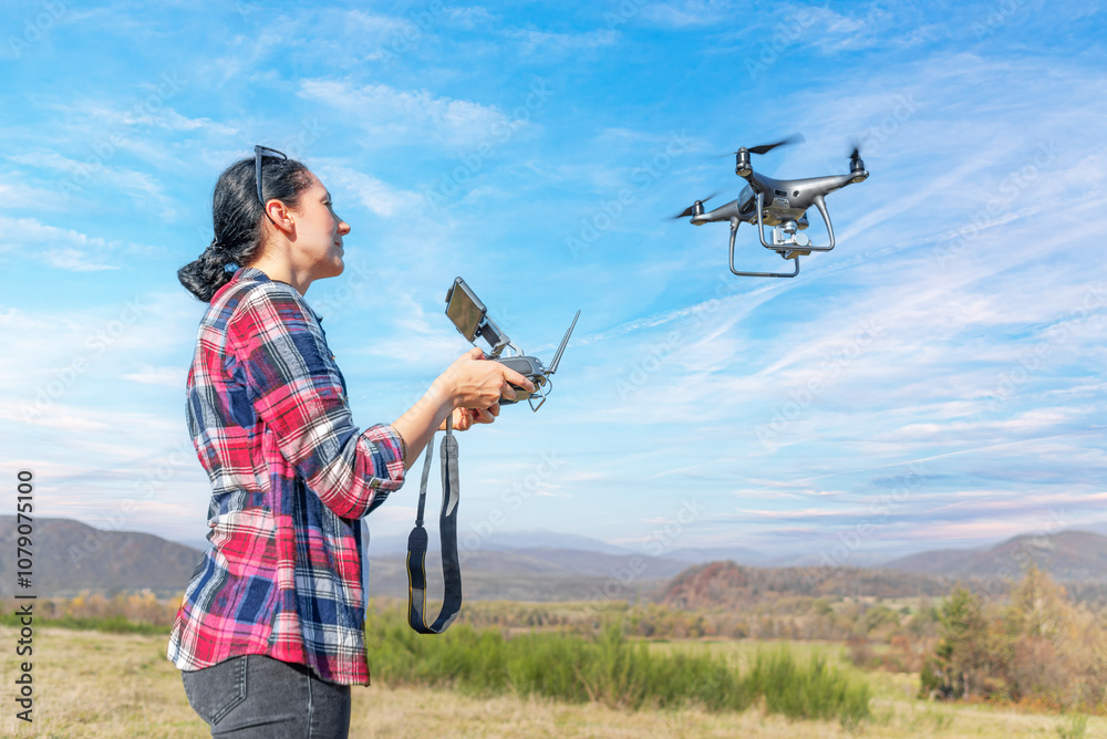 A young woman controls a drone with a remote control in her hands.