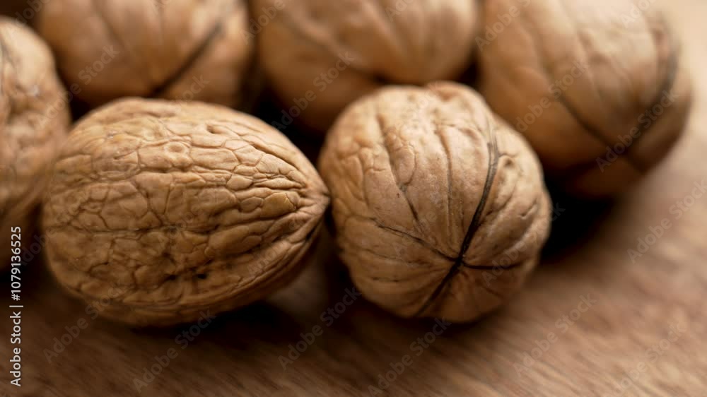 Whole walnuts with natural shells in a close-up shot on a wooden texture. Rich in healthy fats and nutrients, these nuts are perfect for snacking or cooking. Macro. Rotation Whole walnuts with natural shells in a close-up shot on a wooden texture. Rich in healthy fats and nutrients, these nuts are perfect for snacking or cooking. Macro. Rotation