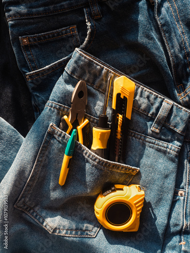 Construction tools in blue jeans pocket close up photo