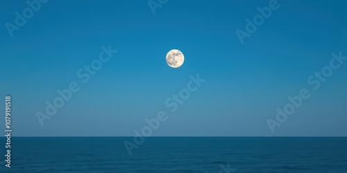 Full moon rising in a clear night sky over a calm and tranquil empty ocean with copy space, water, dark