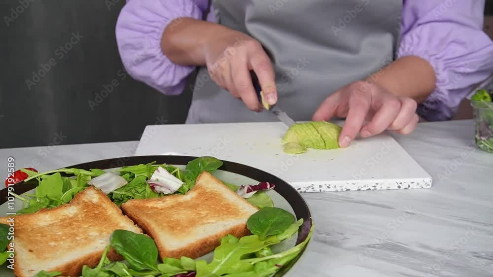 Chef preparing fresh avocado toasts with greens in modern kitchen setting Chef preparing fresh avocado toasts with greens in modern kitchen setting